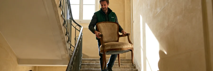 Déménageur portant une chaise dans un escalier en pierre dijonnais